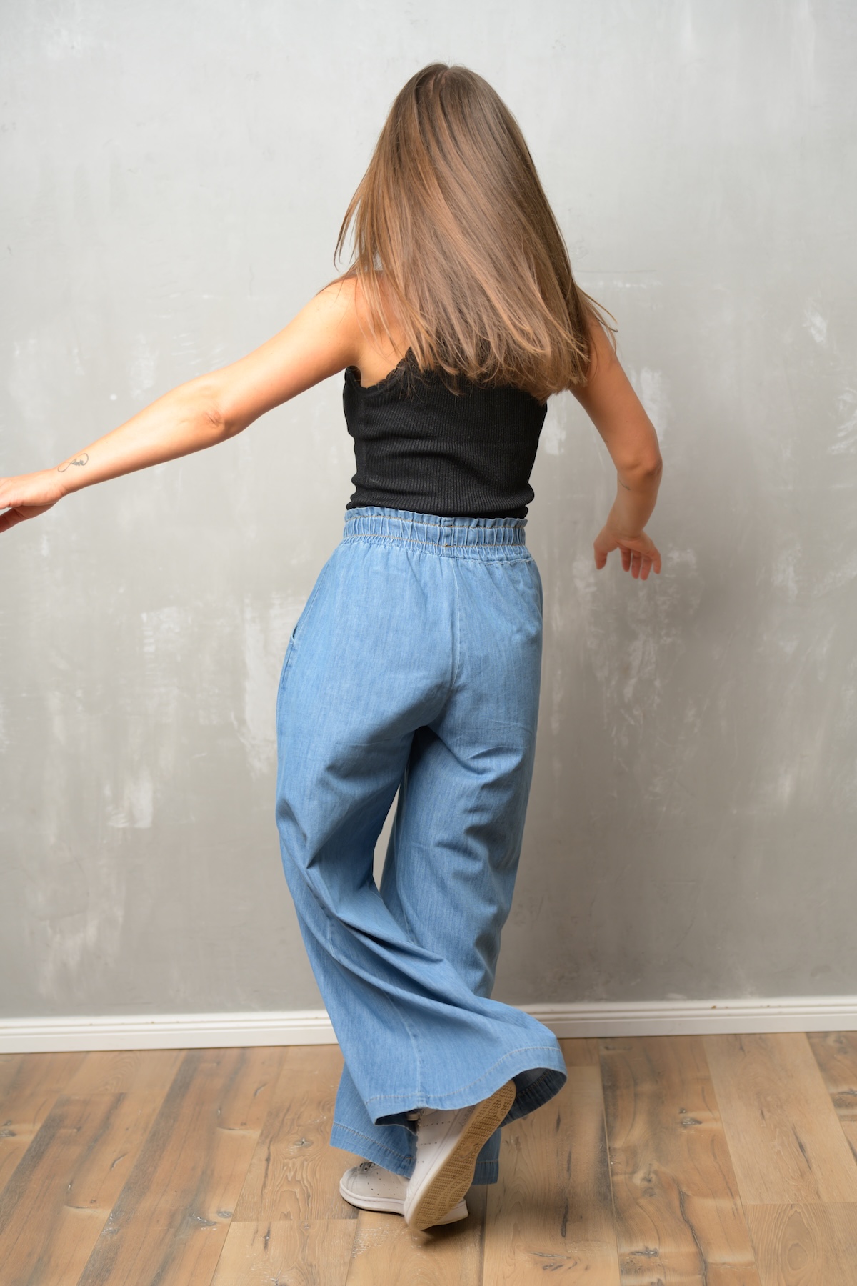 Giulia Barile, DGSv-zertifizierte systemische Supervisorin in Köln und Coach für berufliche Neuorientierung, trägt ein schwarzes Top und eine blaue Jeans. Man sieht sie in Bewegung von hinten, während sie eine Pirouette dreht