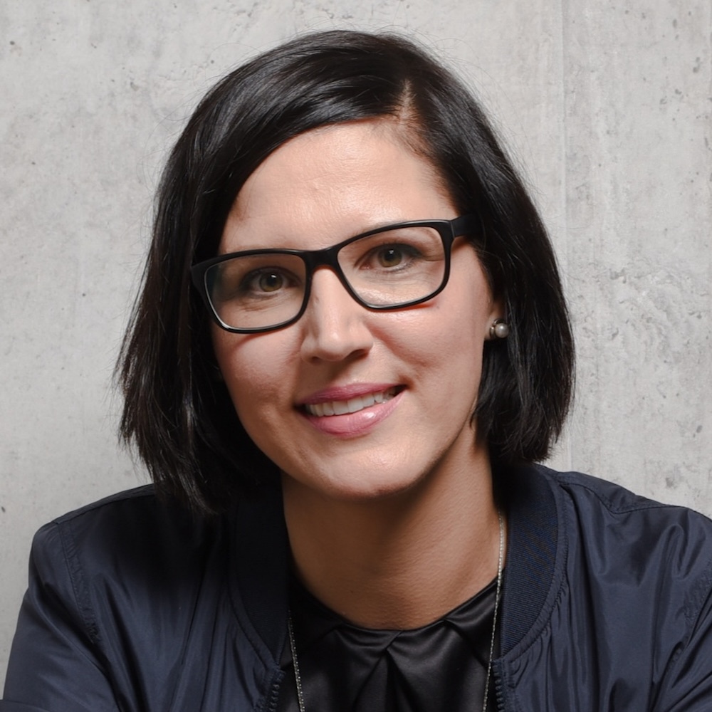 Testimonial und Portrait von Julia, Teilnehmerin des Online-Programms Mit Klarheit in deine berufliche Zukunft. Sie trägt eine Brille mit schwarzem Rand und ein schwarzes Shirt und Jacke.