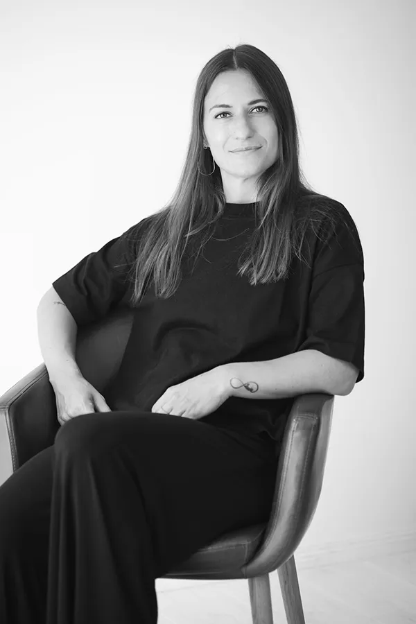 Giulia Barile, DGSv-zertifizierte systemische Supervisorin in Köln und Coach für berufliche Neuorientierung, sitzt auf einem Stuhl und schaut in die Kamera