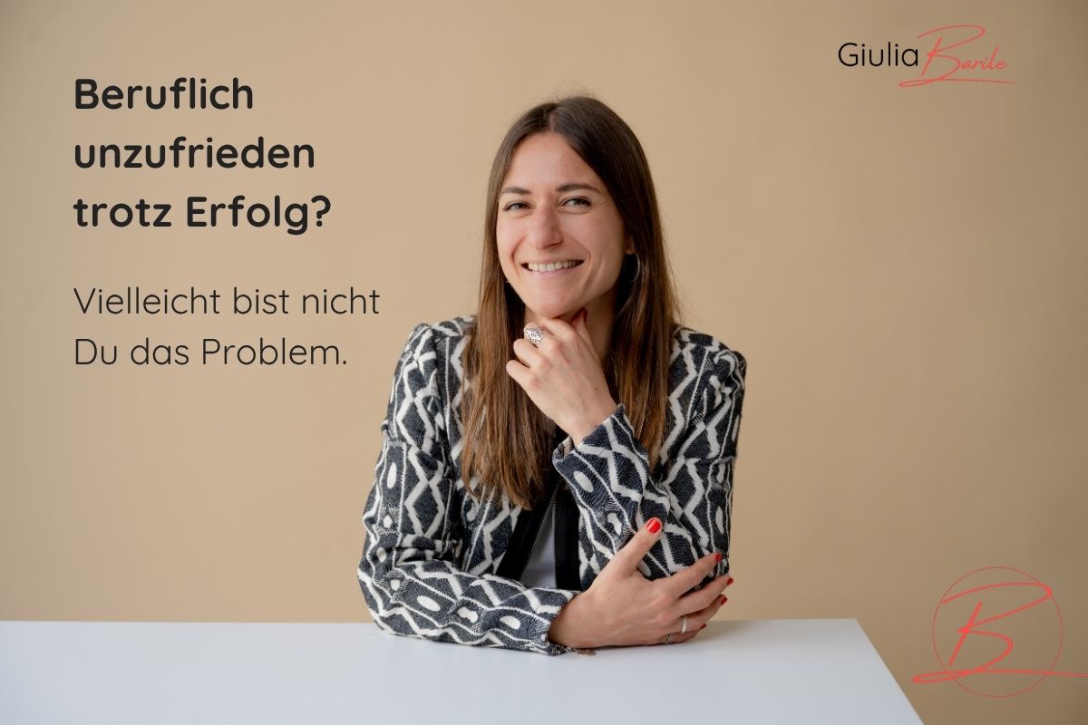 Supervisorin und Coach Giulia Barile sitzt an einem weißen Schreibtisch mit beigen Hintergrund. In der oberen linken Ecke der Schriftzug: Beruflich unzufrieden trotz Erfolg? Vielleicht bist nicht du das Problem.