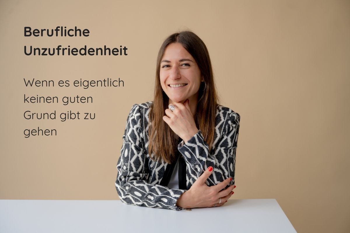 Supervisorin und Coach Giulia Barile sitzt an einem weißen Schreibtisch mit beigen Hintergrund. In der oberen linken Ecke der Schriftzug: berufliche Unzufriedenheit. Wenn es eigentlich keinen guten Grund gibt zu gehen.